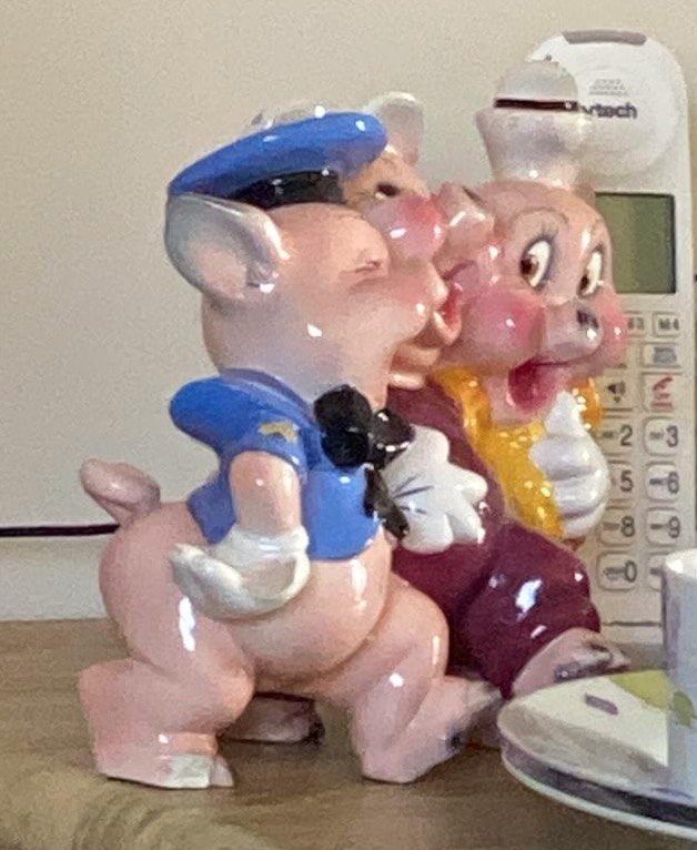 Roslyn&rsquo;s three ceramic pigs, a policeman, a chef and a dancer, standing arm in arm on a wooden side table